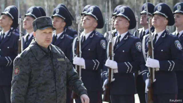 Исполняющий обязанности президента Украины Александр Турчинов маришиорует на фоне украинских военных