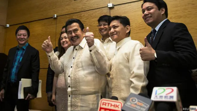 埃斯特拉达（中）在菲律宾驻香港总领事馆的记者会上举起胜利手势（23/4/2014）