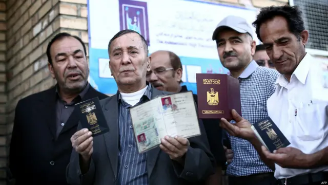 مجموعة من الرجال يحملون جوازات سفرهم العراقية