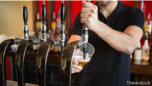 Бармен наливает пиво в стакан
