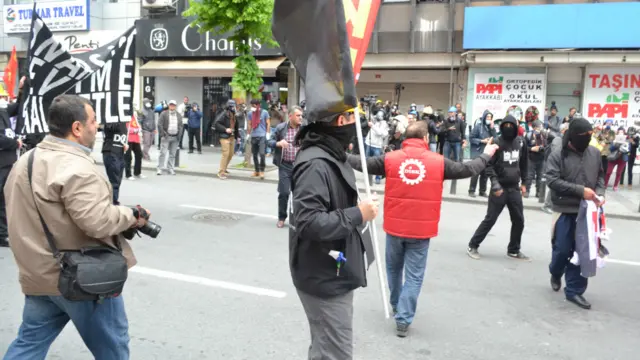 یکی از فعالین اتحادیه کارگری سعی می کند جلوی پرتاب سنگ به سوی پلیس از سوی آنارشیست های سیاه پوش را بگیرد 