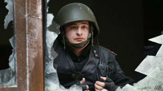 Policía ucraniano mira por la ventana rota de la oficina del fiscal regional