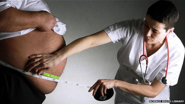 Una enfermera mide la barriga de hombre obeso