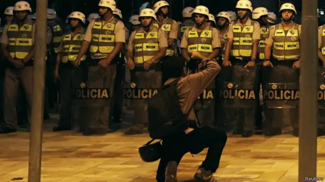 Repórter fotográfico tira foto de policiais antes de protesto em SP, em abril (Reuters)