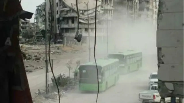 اتوبوس‌های حامل پیکارجویان در حال ترک بخش قدیمی شهر حمص است