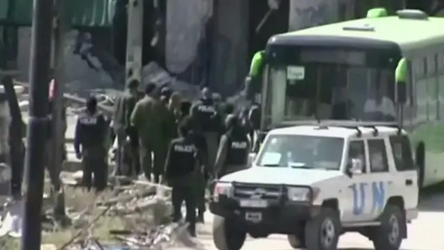 叛军士兵排队登上绿色的巴士和一辆有联合国标志的吉普车。