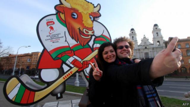 Туристы фотографируются в Минске на фоне эмблемы чемпионата мира по хоккею