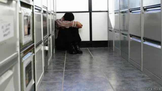 Un hombre sentado contra unos archivadores en el piso de una oficina