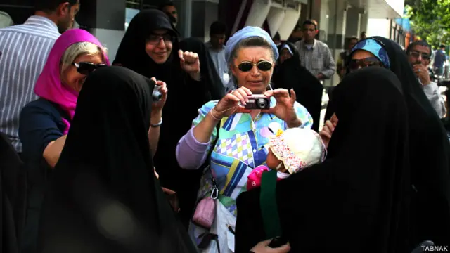 زنان رهگذر در خیابان فاطمی از کودکی که در آغوش یکی از تظاهرکنندگان است، عکس می‌گیرند (عکس: علی علیزاده)