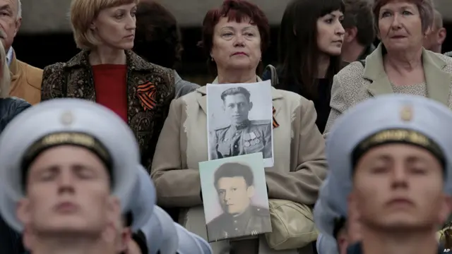 Una mujer sostiene fotos de familiares que pelearon en la Segunda Guerra Mundial
