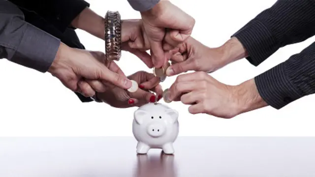 Varias personas meten monedas en una alcancía