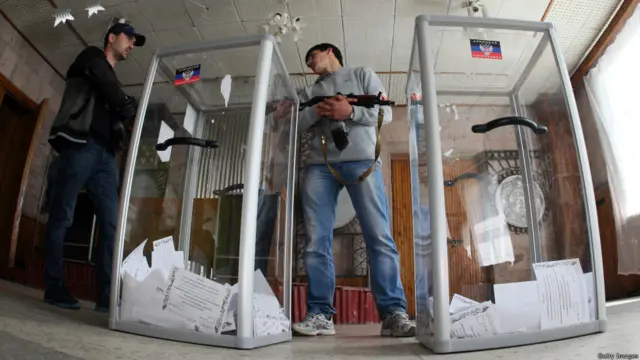 Вооруженные люди рядом с избирательными урнами