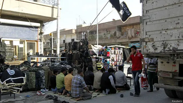 Сирийцы молятся в Ракке на фоне джихадистских флагов