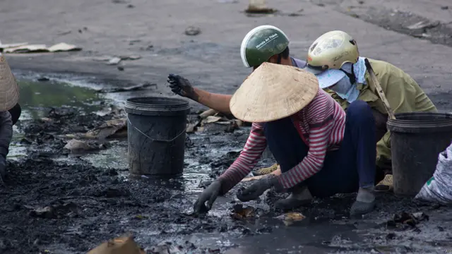 Người dân thị trấn Di An, Bình Dương nhặt các mảnh sắt vụn ở một nhà máy Trung Quốc bị đốt cháy sau cuộc bạo động.