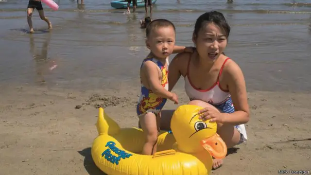 أم وطفلها يلعبان ببطة عائمة قرب الشاطئ