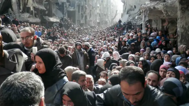 ایک شامی پناہ گزین کیمپ کے مکین اقوام متحدہ کی خوراک کی تقسیم کی مہم میں خوراک حاصل کرنے کے لیے اس طرح امڈ آئے