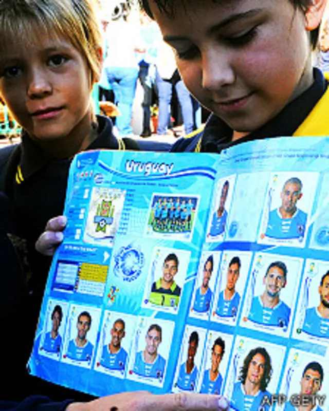 Niños en Uruguay con un album de figuritas que muestra a los jugadores de la selección de Uruguay