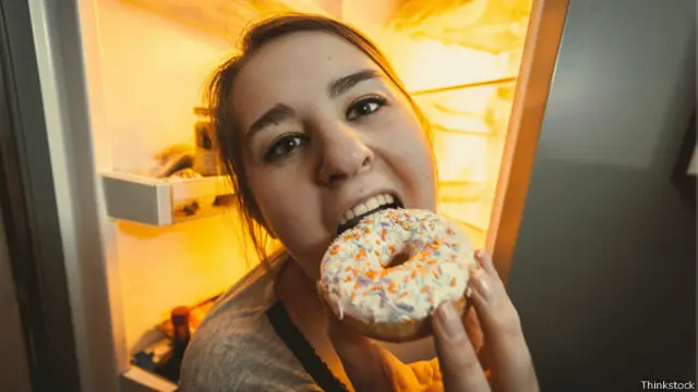 Mujer comiendo en la noche