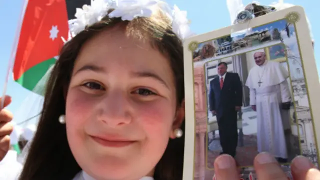 Menina segura foto do papa com o rei Abdullah da Jordânia (AP Photo/Raad Adayleh)