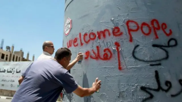 فلسطينيون يكتوب على الجدران عبارات الترحيب بالبابا.