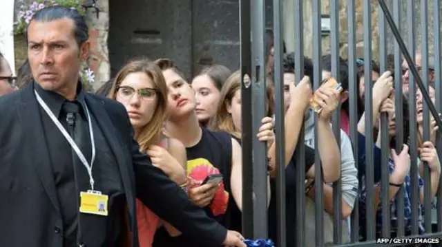 معجبون مصطفون وأمامهم رجل أمن