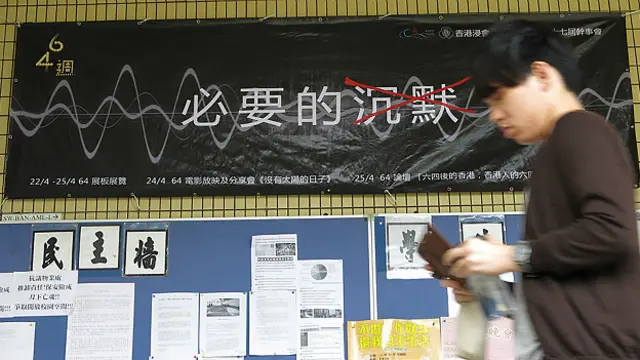 香港浸会大学校园内一名学生走过学生会宣传六四25周年活动的横幅