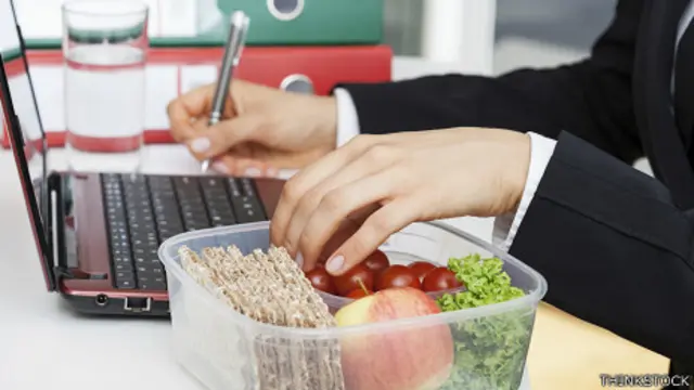 Persona almorzando en el escritorio