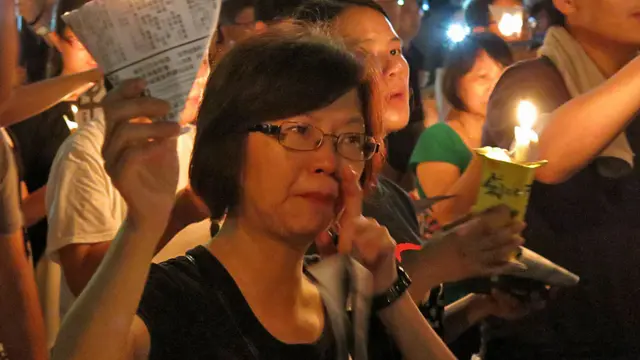 香港維多利亞公園六四燭光晚會上一名女士用手指拭淚（4/6/2014）