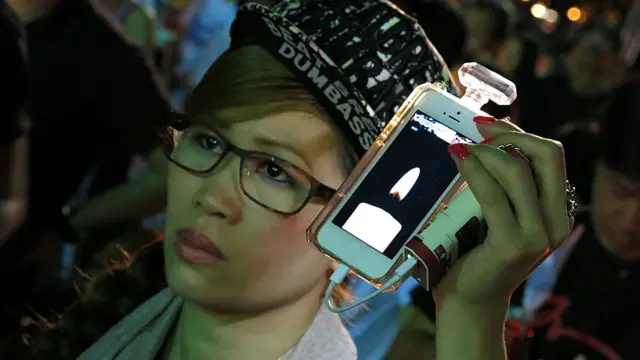 香港維多利亞公園六四燭光晚會上一位女士利用手機展示虛擬蠟燭（4/6/2014）