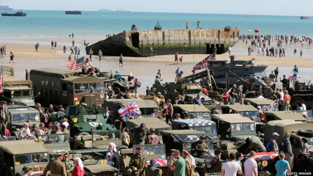 在金色海滩上，陈列着二战时期的军用汽车。