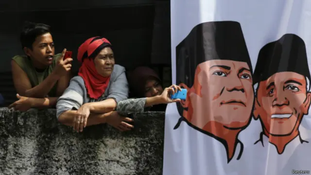 Keluarga di sebuah kampung di Bandung dan spanduk capres Prabowo-Hatta. 
