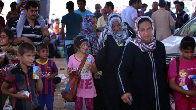 بعض الأسر العراقية التي فرت من نينوى خلال مرورها بنقطة تفتيش كردية، تنتظر الدخول.