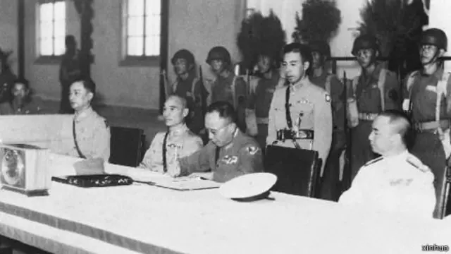 1945年9月9日，中国战区日军投降签字仪式在南京举行，图为中方受降代表何应钦（前右二）在日军降书上签字。 