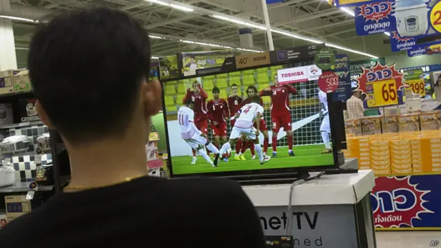 泰国曼谷某购物商场内一名顾客驻足收看电视转播足球比赛（11/6/2014）