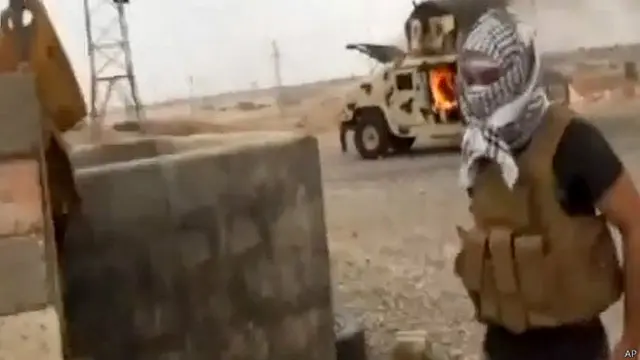 Một tay súng Hồi giáo trước xác xe quân sự của Iraq