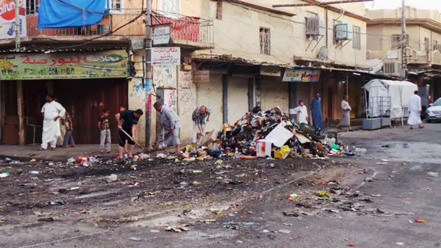 مردم مشغول تمیز کردن خیابانی در شمال شهر موصل عراق هستند