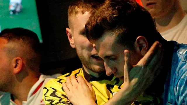 انگلش ٹیم کے مداح انگلینڈ کی ایک سپورٹس بار میں انگلین کی کارکردگی پر ایک دوسرے کو تسلی دے رہے ہیں۔