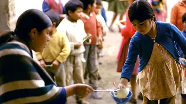 Niña recibiendo un plato de comida en Ecuador 