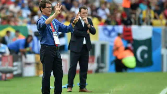 د روسیې لوبډلې روزونکی فبیو کپېلو لوبغاړو ته په لاس لارښوونه کوي، څنګ ته یې د بلجیم لوبډلې روزونکی مارک ویلمټ هم لیدلی شئ.