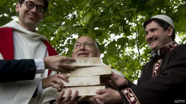 As mãos do pastor, do rabino e do imã sob símbolos tijolos
