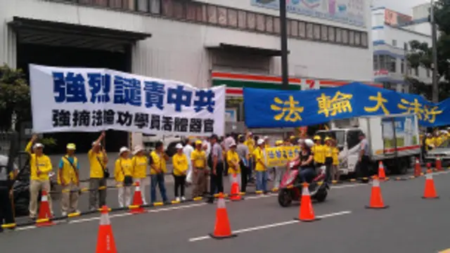 法輪功抗議團體在一旁默默舉著布條，抗議中共迫害法輪功。（BBC中文網特約記者嚴思祺攝）