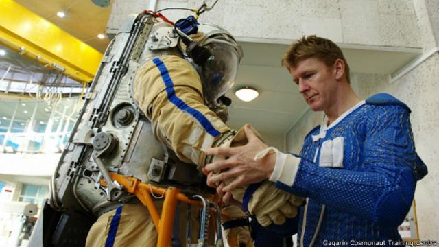 Американский астронавт изучает российский скафандр