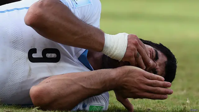 Suárez tendido y tomándose la boca tras el incidente con Chiellini