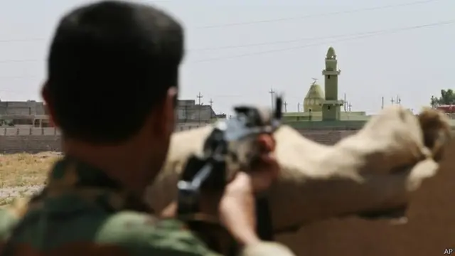 Um combatente curdo assiste ao posicionamento do ISIS em Tuz Khormato, no Iraque (AP)