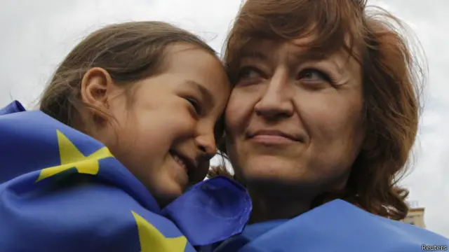 سيدة أوكرانية وابنتها تلتفان بعلمي الاتحاد الأوروبي وأوكرانيا في ميدان الاستقلال بعد توقيع الاتفاق التجاري بين أوكرانيا والاتحاد.