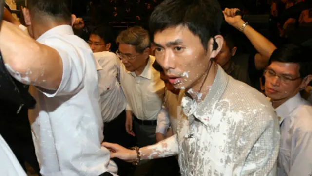 在遭抛漆袭击后,张志军面色沉重在随行人员的护卫下进入茶叙会馆。