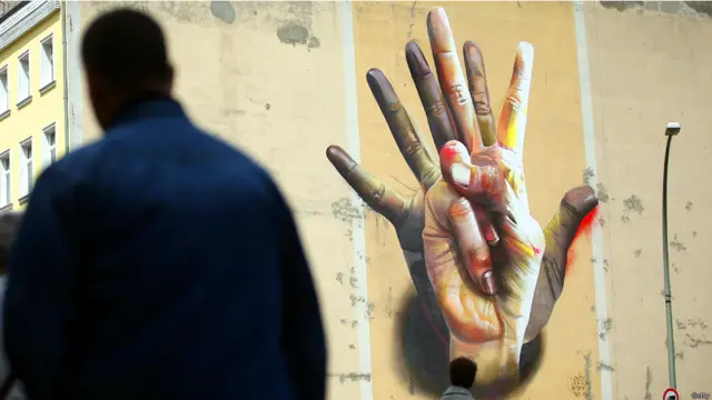جدارية ضخمة بعنوان "تحت الكف" في حي كرويزبيرغ ببرلين. (صورة غيتي)
