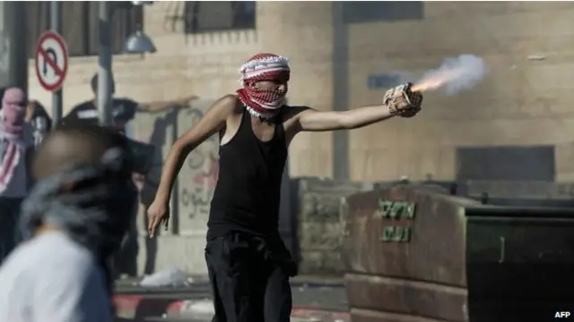 متظاهر فلسطيني يلقي مادة حارقة على قوات الأمن الإسرائيلية في بلدة شعفاط.