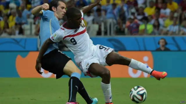Pemain Kosta Rika, Joel Campbell (kaos putih), berduel dengan pemain belakang Uruguay.