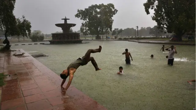 بدھ کو دہلی میں ہونے والی بارش کے دوران نوجوان موسم کا مزہ لیتے ہوئے۔